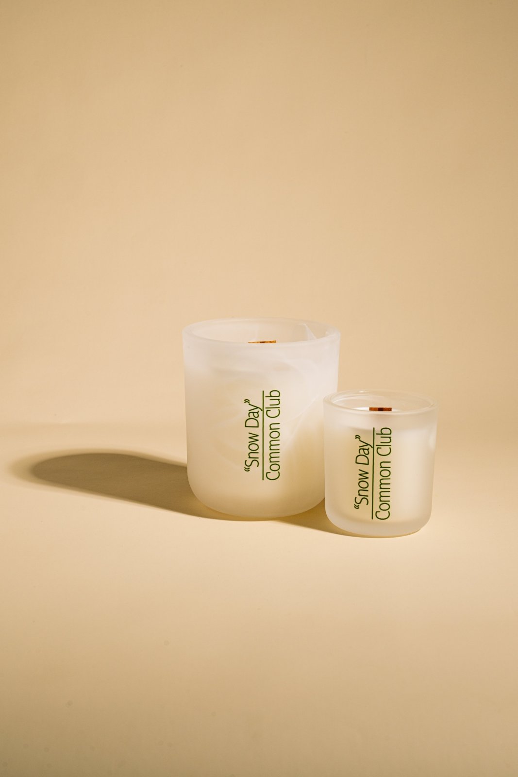 Two white candles with 'Common Club' branding on a beige background
